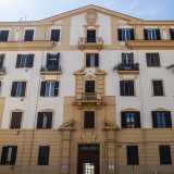 La dimora si innalza su cinque piani scanditi da una sequenza parallela di finestre con imposte marroni...